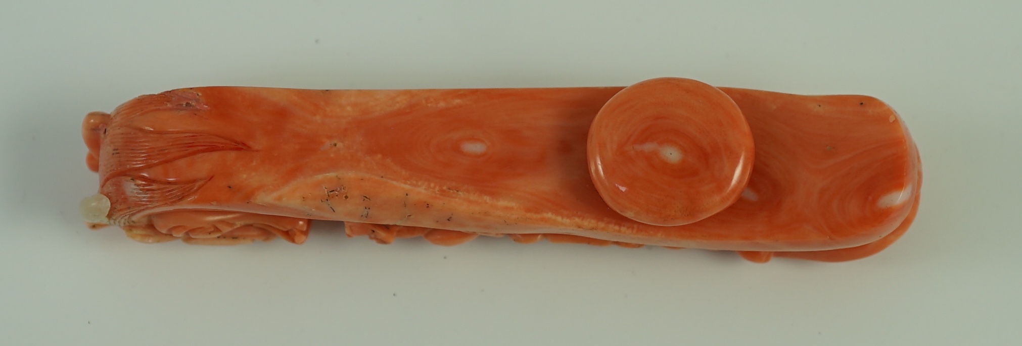 A rare Chinese coral 'dragon' belt hook 18th/19th century, 9.2 cm long, small loss to dragon horn, wood stand